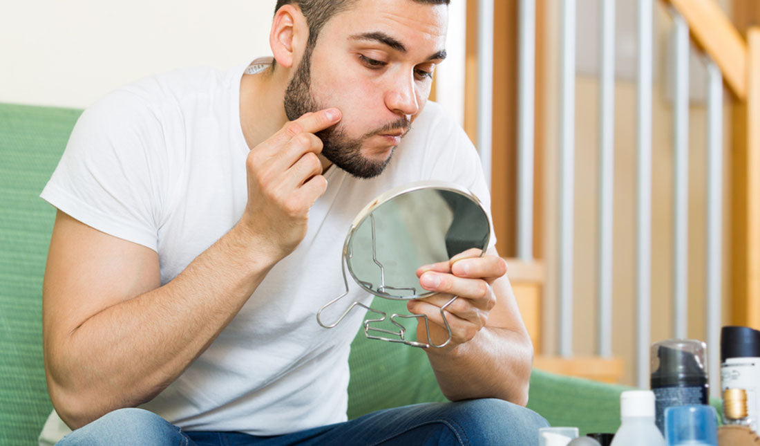 guy popping pimple on face