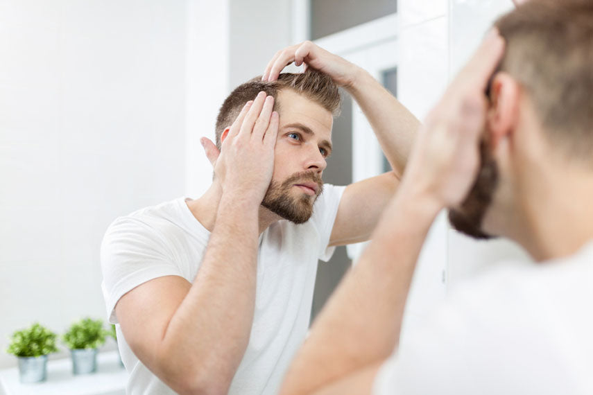 man checking hair in mirror