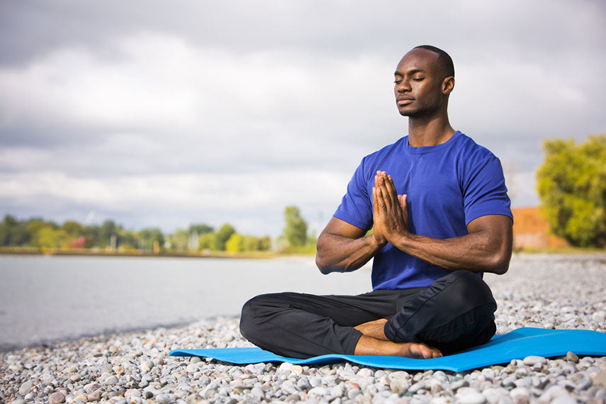 man doing yoga on the beach