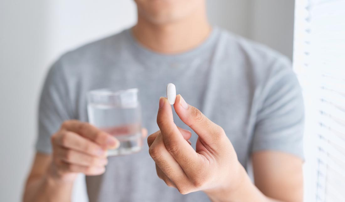 holding pill with glass of water