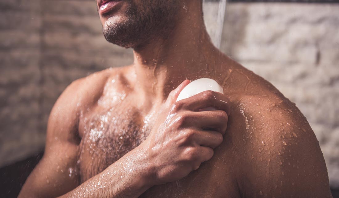 man scrubbing chest with soap