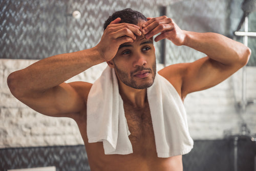 man popping pimple in bathroom