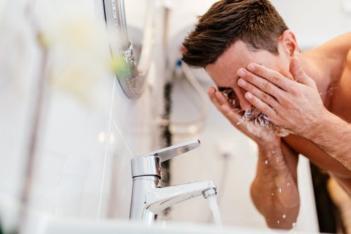 man washing face over sink