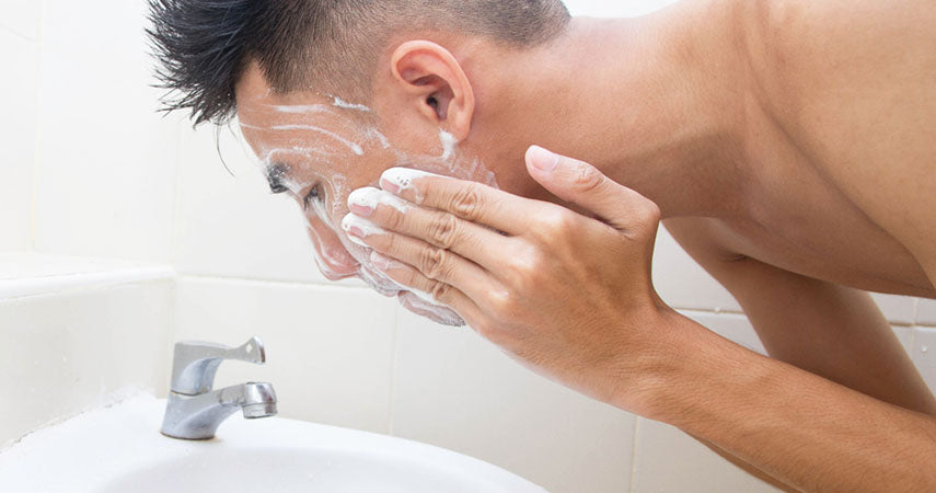 man washing face over sink