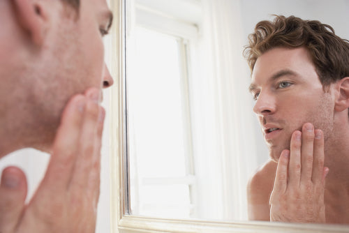 young man examining his face